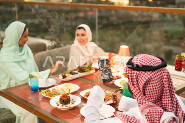 رجل سعودي يصور الطعام في مطعم خارجي