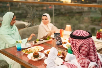 رجل سعودي يصور الطعام في مطعم خارجي