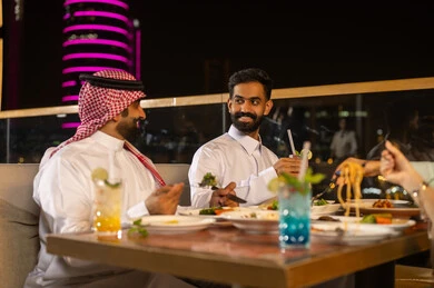 Saudi Men Dining at Night Rooftop Restaurant