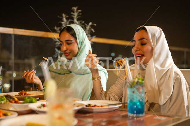نساء عربيات يتناولن العشاء في مطعم خارجي ليلًا