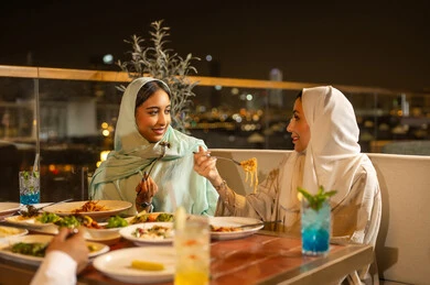 نساء عربيات يتناولن العشاء في مطعم خارجي ليلاً