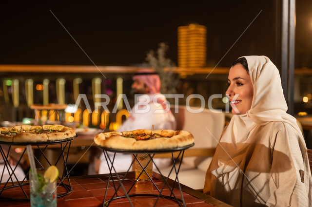 امرأة سعودية في مطعم خارجي مع وجبة بيتزا