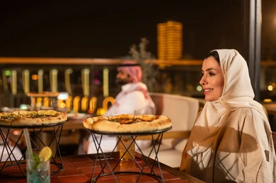امرأة سعودية في مطعم خارجي مع وجبة بيتزا