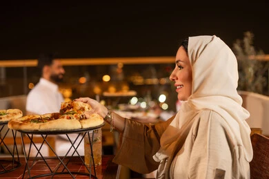 امرأة سعودية تتناول البيتزا في مطعم خارجي ليلاً