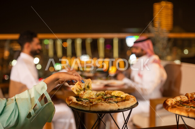 تناول البيتزا في مطعم سعودي على السطح ليلاً