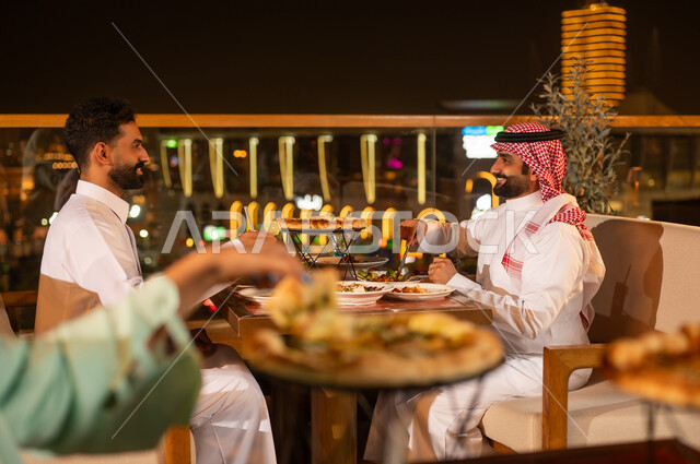 Saudi Men Dining at Rooftop Restaurant Night