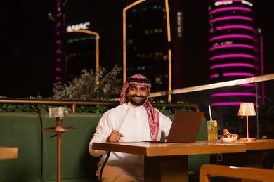 Saudi Man Using Laptop at Night Outdoor Restaurant
