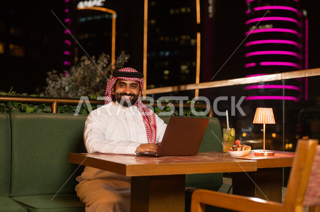 Saudi Businessman Working on Laptop at Night Restaurant