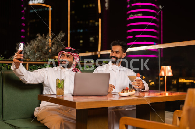 Saudi Men Taking Selfie with Laptop at Night Restaurant