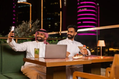Saudi Men Taking Selfie with Laptop at Night Restaurant