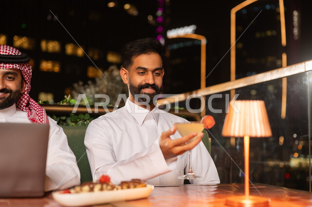 رجل سعودي في مطعم فاخر على السطح ليلاً