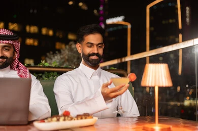 رجل سعودي في مطعم فاخر على السطح ليلاً