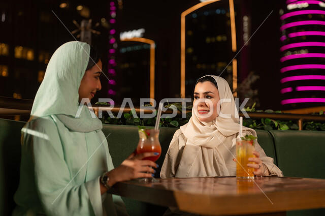 نساء عربيات في مطعم بمدينة ليلاً مع مشروبات