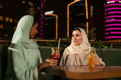 نساء عربيات في مطعم بمدينة ليلاً مع مشروبات