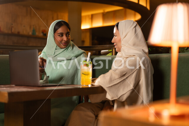 سيدات سعوديات يعملن على كمبيوتر محمول في مطعم