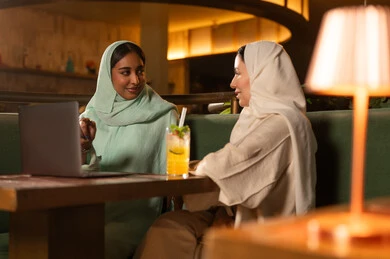 سيدات سعوديات يعملن على كمبيوتر محمول في مطعم