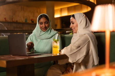 نساء عربيات يستخدمن المحمول في مقهى ليلاً