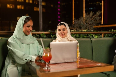 Saudi Women Using Laptop at Outdoor Night Restaurant