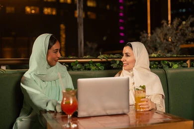 نساء عربيات مع كمبيوتر محمول في مطعم ليلاً