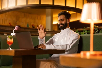 رجل سعودي يستخدم اللابتوب لمكالمة فيديو في مطعم