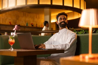 رجل سعودي يعمل على الكمبيوتر المحمول في مطعم