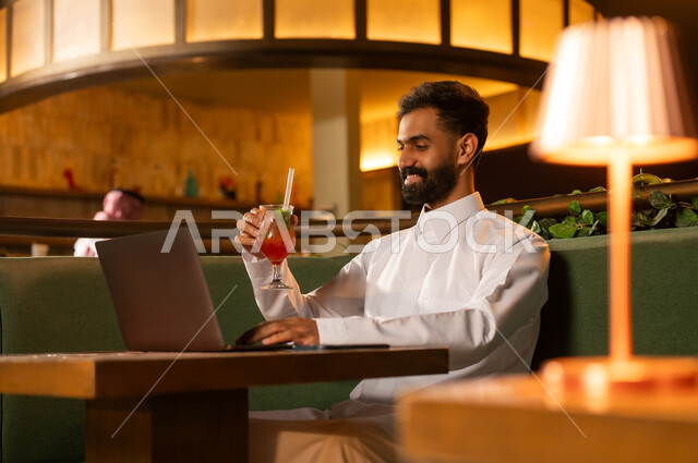 رجل أعمال سعودي يعمل على اللابتوب في ردهة فاخرة