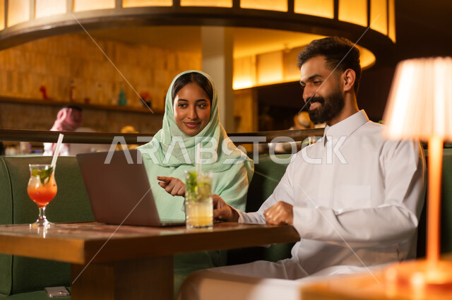 زوج سعودي يستخدم كمبيوتر محمول في مطعم