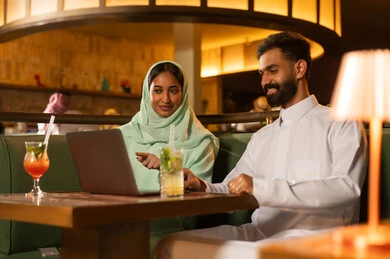 زوج سعودي يستخدم كمبيوتر محمول في مطعم