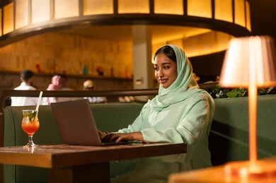 Arab Woman Working on Laptop inside a Restaurant Cafe