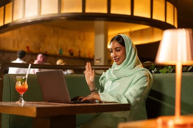 امرأة سعودية تستخدم اللابتوب لمكالمة فيديو في مطعم