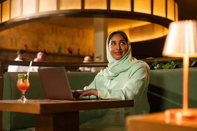 امرأة سعودية مهنية تستخدم الكمبيوتر المحمول في مقهى عصري