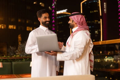 رجال أعمال سعوديون يستخدمون المحمول في شرفة ليلية