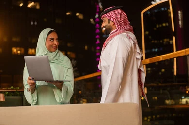 رجل وامرأة من السعودية يعملان على المحمول ليلاً