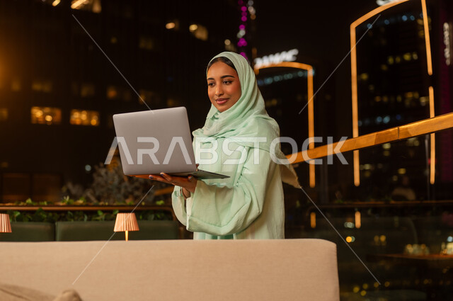 Arab Woman Working on Laptop at Dubai Rooftop Night