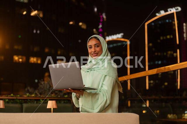 امرأة عربية مع كمبيوتر محمول في مدينة ليلاً