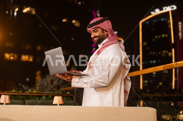 رجل أعمال سعودي يستخدم المحمول ليلاً في الخارج