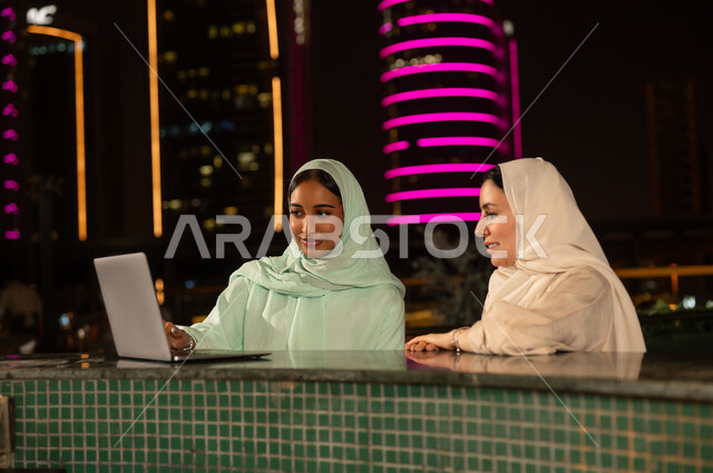 سيدات سعوديات يعملن على كمبيوتر محمول في الرياض ليلاً