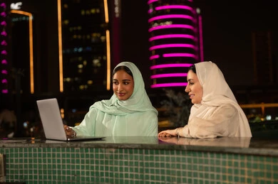 سيدات سعوديات يعملن على كمبيوتر محمول في الرياض ليلاً