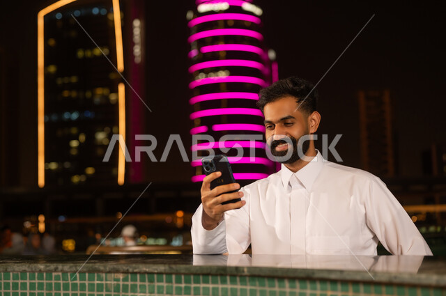 Saudi Man Using Smartphone in City at Night
