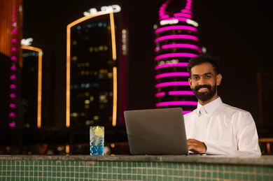 رجل عربي يستخدم الكمبيوتر المحمول ليلاً في المدينة