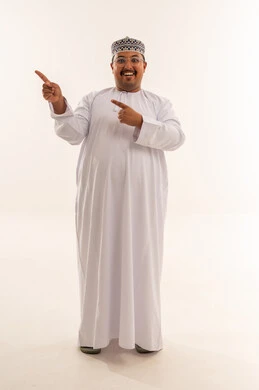 رجل عُماني يرتدي الدشداشة والكمة ويشير للجانب بخلفية بيضاء