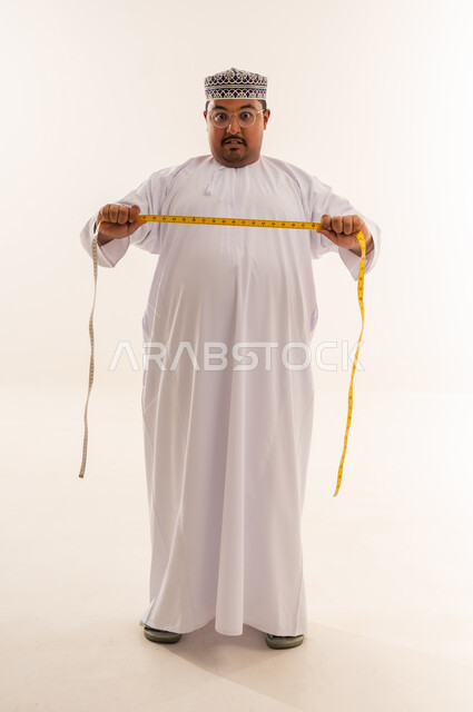 رجل عماني بدين مع شريط قياس على خلفية بيضاء