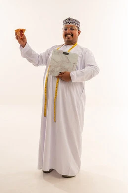 رجل عماني يحمل بيتزا وميزان قياس الوزن