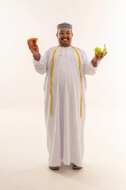 رجل عُماني يختار بين البيتزا والفاكهة في الاستوديو