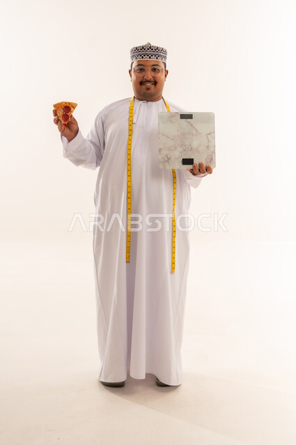 رجل عماني مع بيتزا وميزان قياس في الاستوديو
