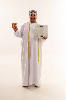 رجل عماني مع بيتزا وميزان قياس في الاستوديو