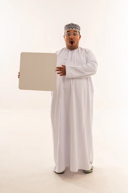 رجل عماني مندهش يمسك لوحة بيضاء فارغة