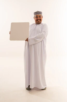 رجل عماني يرتدي الدشداشة يمسك لوحة بيضاء فارغة