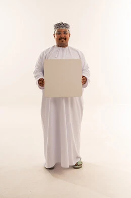 رجل عماني بالزي التقليدي يحمل لوحة بيضاء فارغة