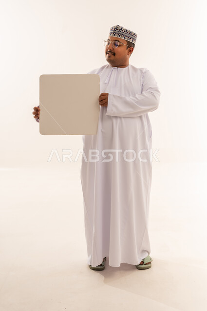 رجل عماني يحمل لوحة بيضاء في الاستوديو